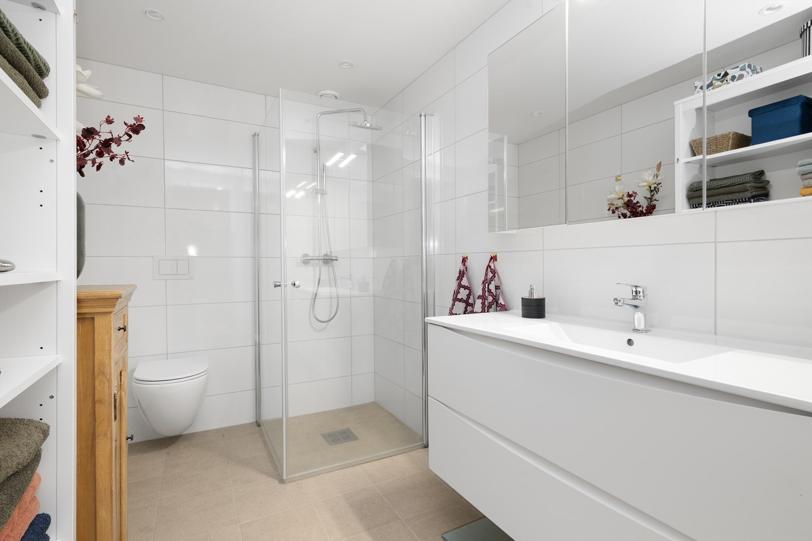 Flott, helfliset bad med varmekabler i gulv. Badet er innredet med veggmontert toalett, dusjhjørne og servantinnredning med skuffer og overskap med speil. Galleribilde