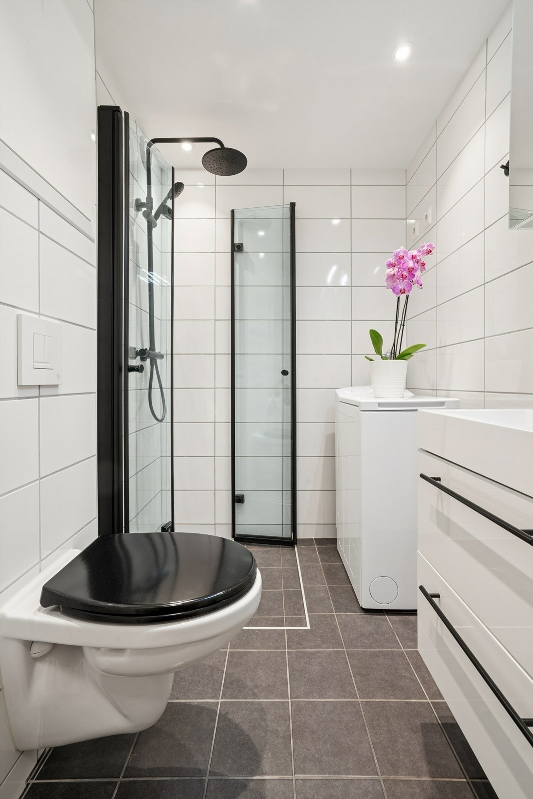 Lekkert baderom med flislagte overflater og komfortabel gulvvarme. I himling er det malte slette overflater med innfelte downlights. Galleribilde