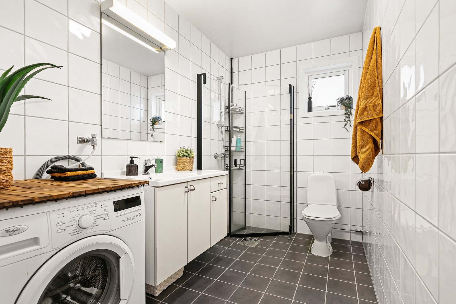 Bad fra byggeår har heldekkende servant med skapseksjon, toalett og et dusjhjørne med hengslede glassvegger Galleribilde