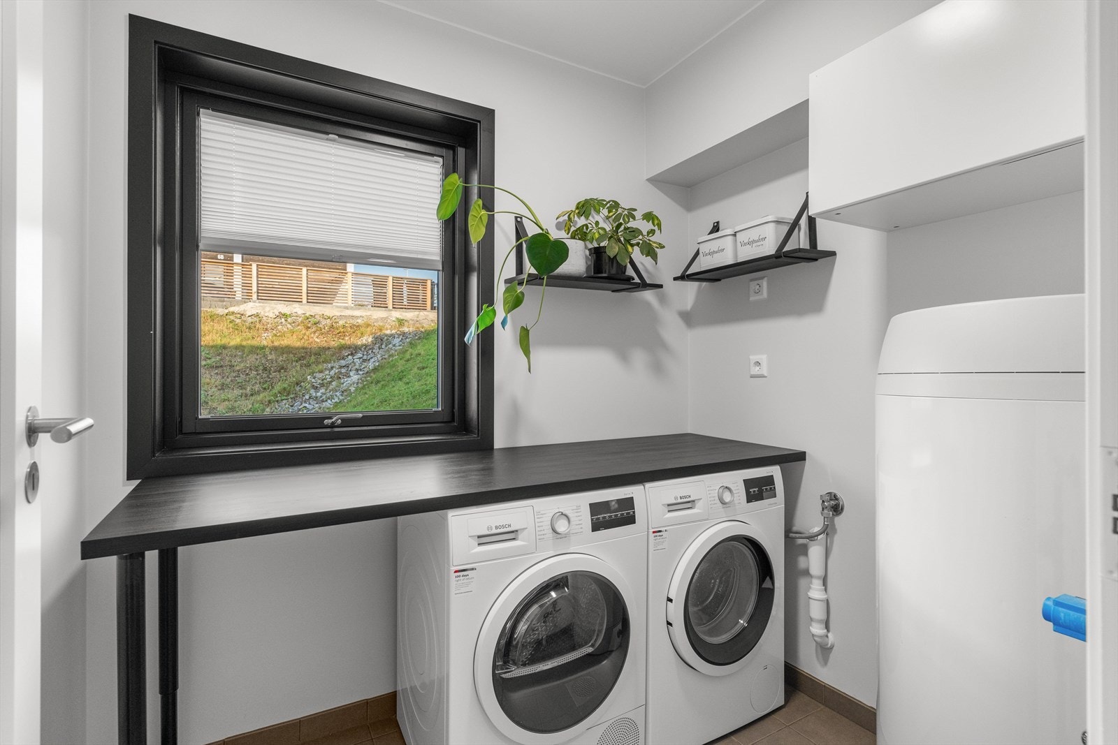 Vaskerommet har opplegg for vaskemaskin og tørketrommel, samt varmtvannsbereder. Det er etablert en benk over vaskemaskin og trommel, samt hengt opp hyller på veggene. Galleribilde