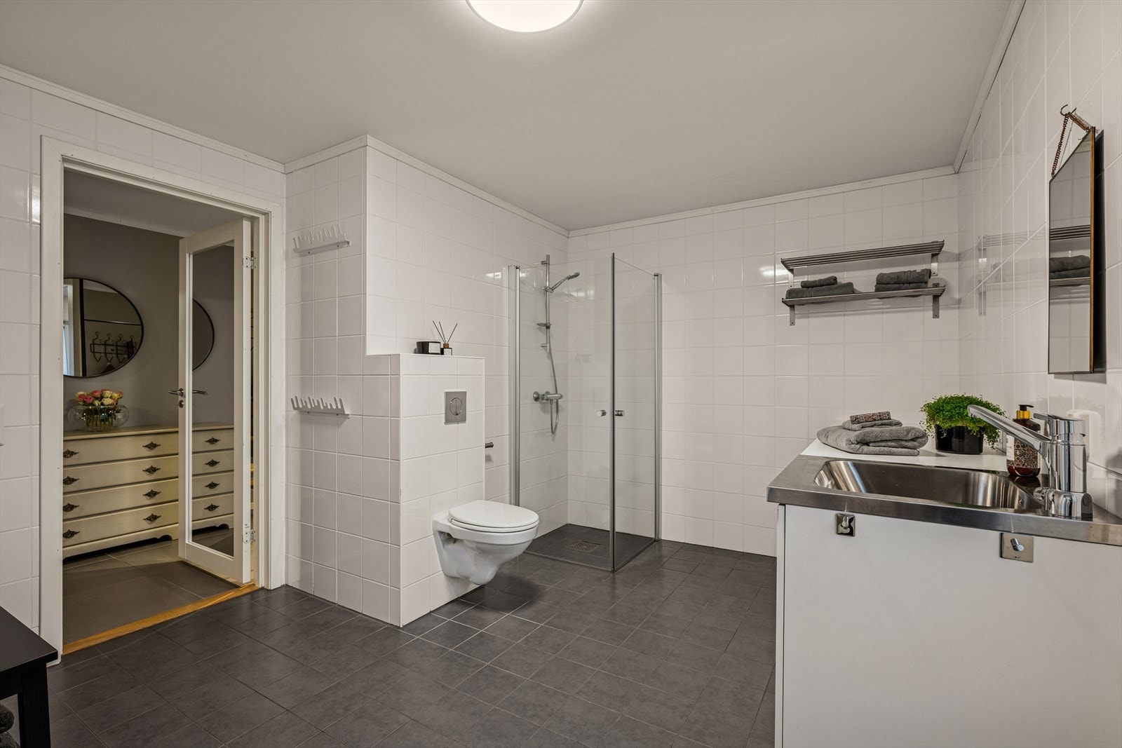 Videre finner man et praktisk bad/vaskerom i 1. etasje med dør som leder direkte ut. Galleribilde