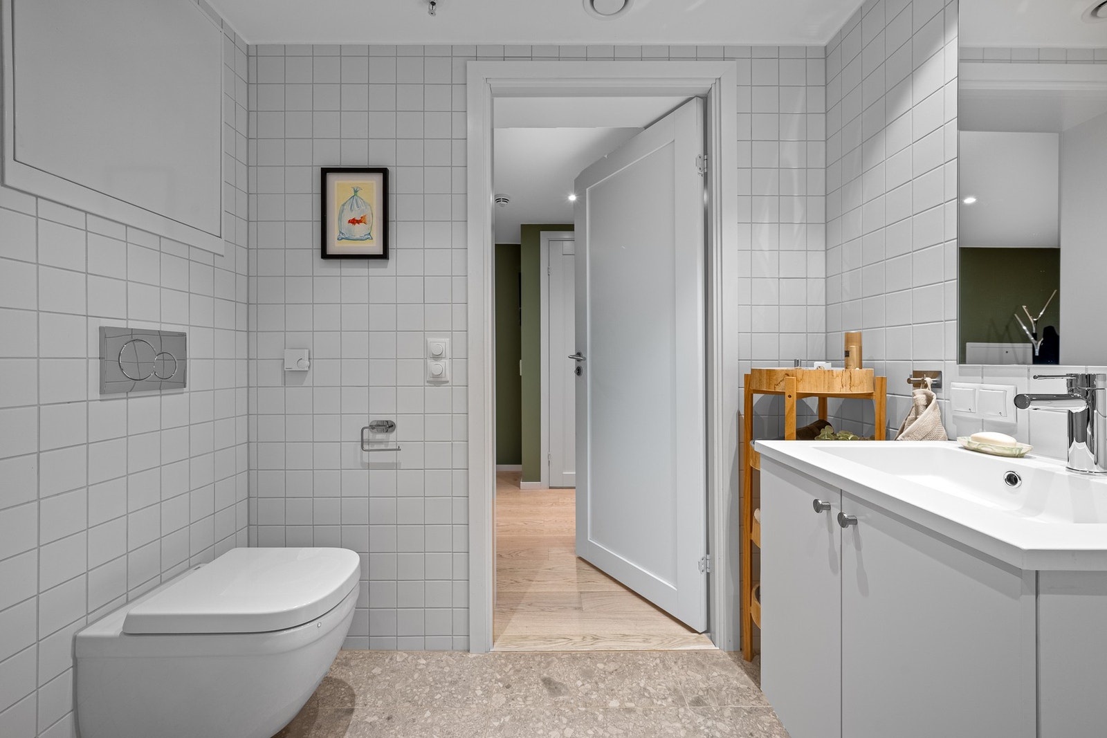 Moderne baderom med flislagte gulv og vegger, samt et slett, hvitmalt tak som gir et rent og tidløst uttrykk. Galleribilde