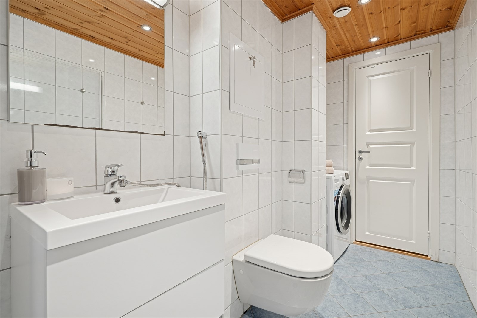 Rommet har innredning med nedfelt servant, veggmontert toalett, dusjhjørne med innfellbare dusjdører og opplegg for vaskemaskin. Galleribilde