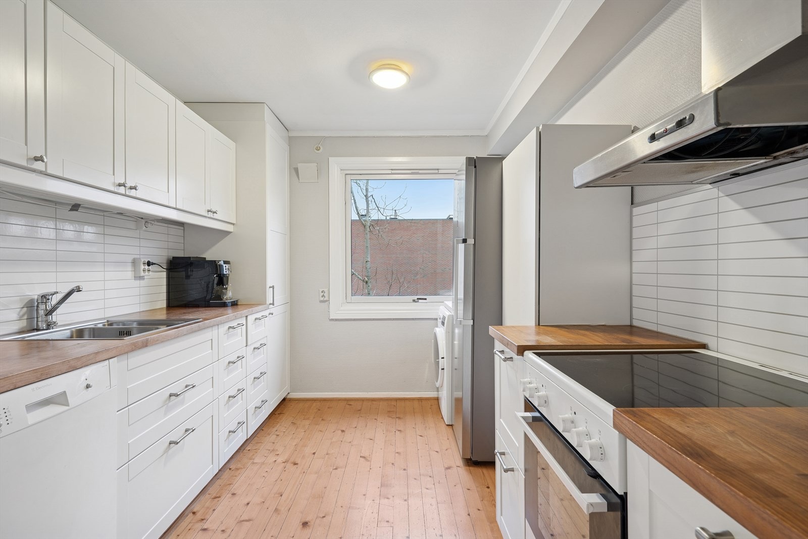 Kjøkkenet har innredning med hvite profilerte fronter og heltre benkeplate. Galleribilde