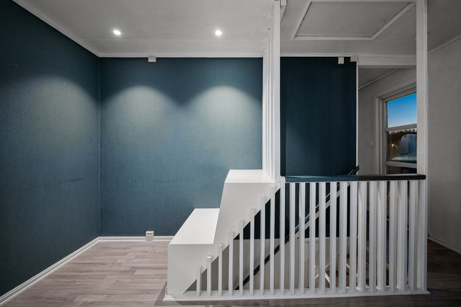 Trapp til underetasje mellom stue og kjøkken som er adskilt med vegg Galleribilde