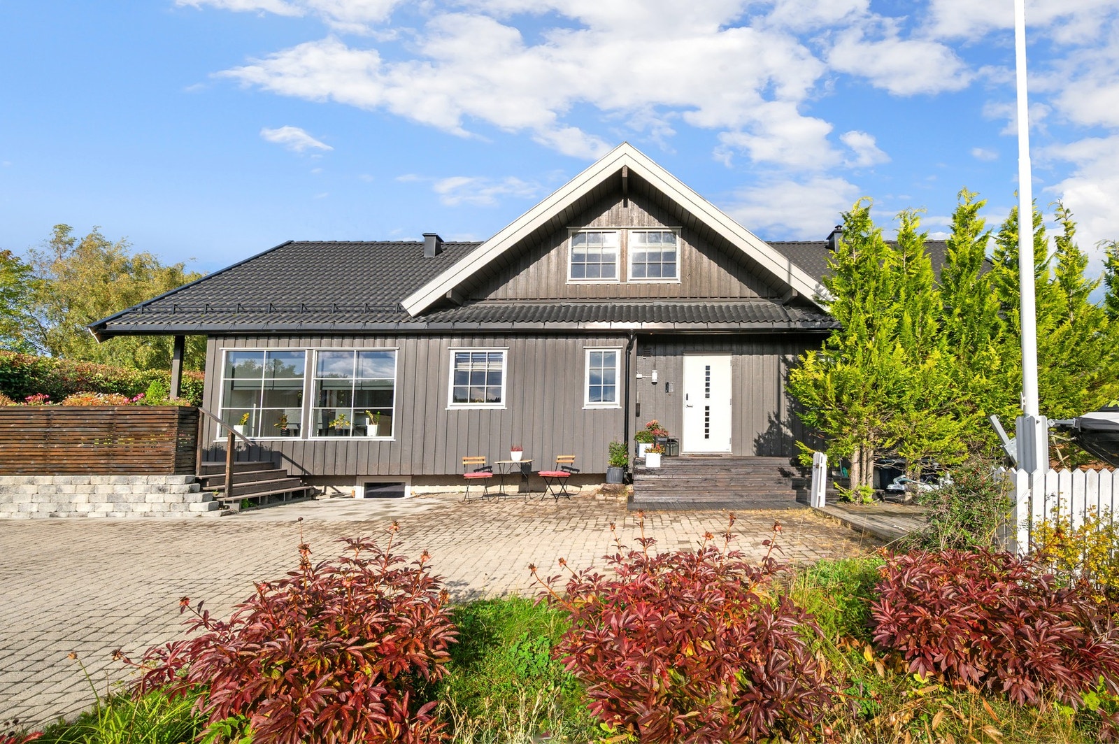 Fint inngangsparti med trapp og en litten platting, samt trapp som fører opp til en solrik terrasse og uteplass. Det er lagt nytt tak på boligen av fagfolk i 2020. Galleribilde