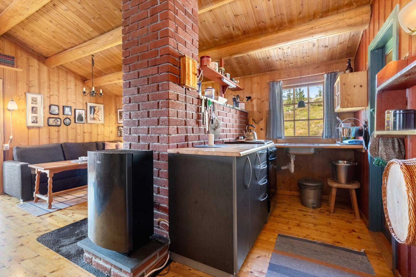 Mindre kjøkken med kjøkkenbenk med benkeslap og skufferekke. Gass komfyr, ellers er det åpen benkeplate med nedfelt oppvaskkum Galleribilde