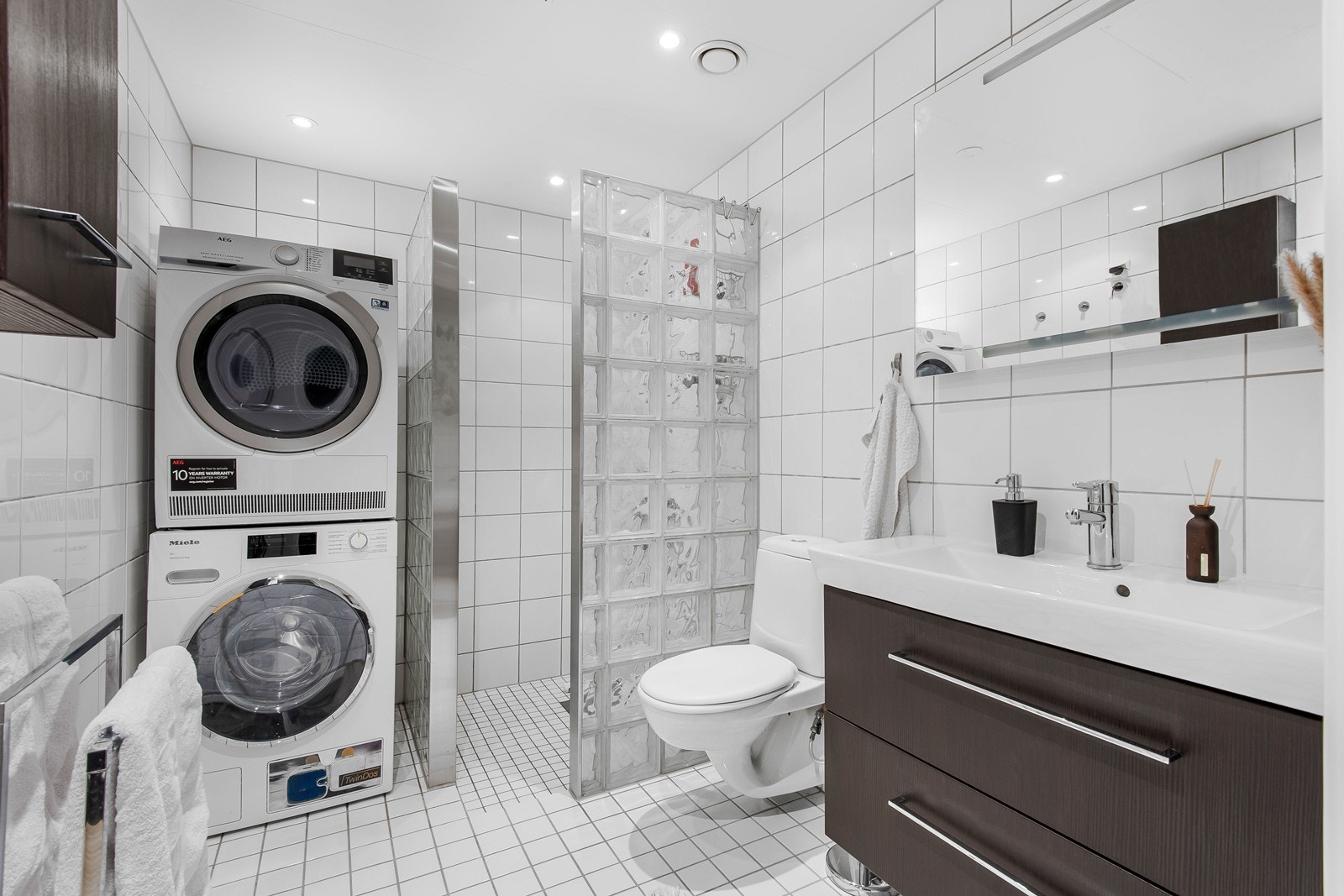 Badet har flislagte overflater, gulvvarme og downlights. Dusjnisjen har vegger av glassbyggerstein og det er en praktisk nisje for vaskesøyle. Galleribilde