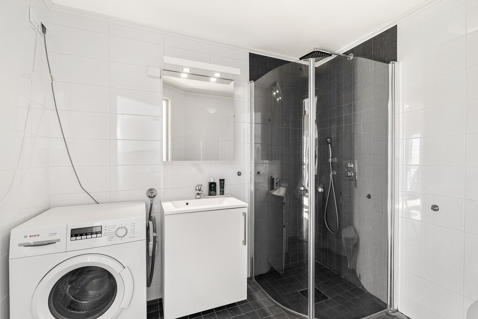 Delikat bad med pene fliser, stilren regndusj, vegghengt wc og varmekabler i gulv. Galleribilde