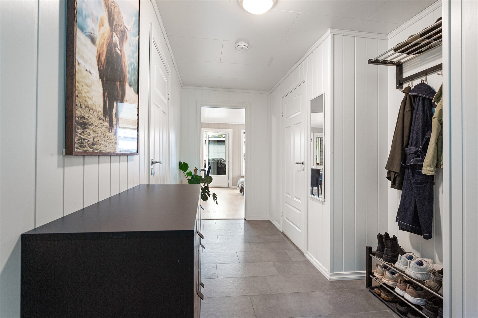 Oversiktlig gang med inngang til bod/teknisk rom, bad, 2 soverom og videre inn til delen med stue og kjøkken Galleribilde