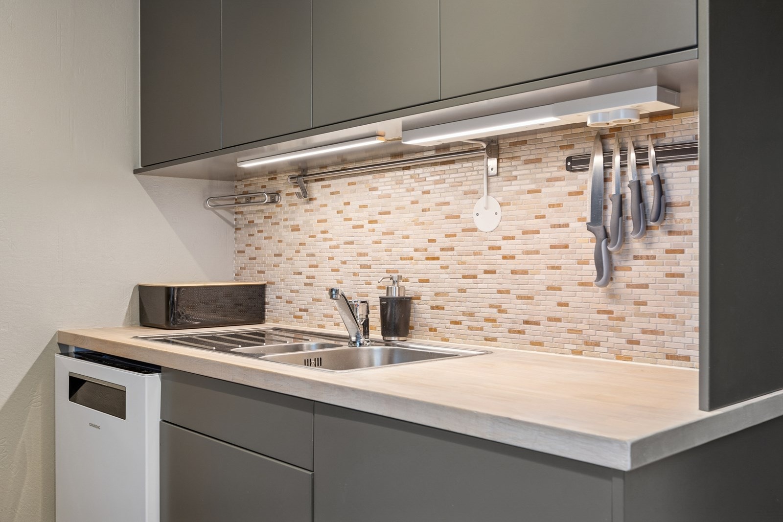 Folierte skrog med slette fronter og heltre benkeplate. Flis på vegg over benkeplate. Opplegg for kjøleskap, komfyr og oppvaskmaskin. Galleribilde