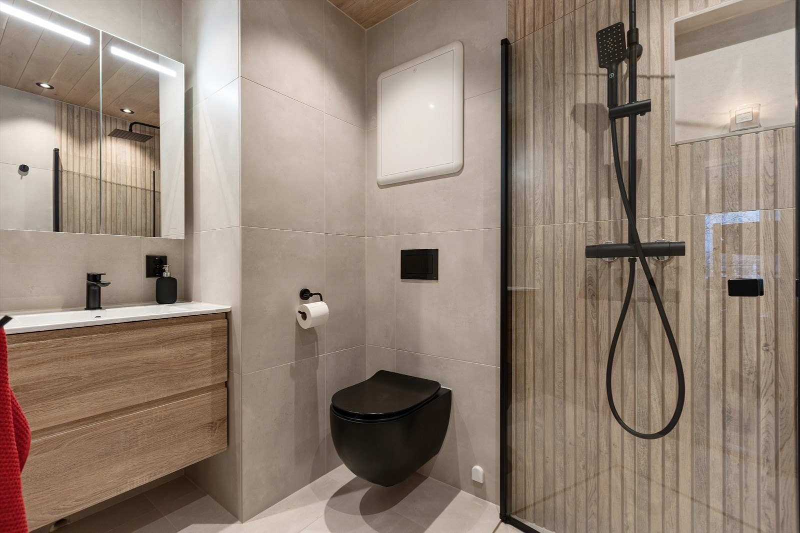 Badet er av god standard med innfellbare dusjdører, toalett, servant med skuffer og speilskap. Galleribilde