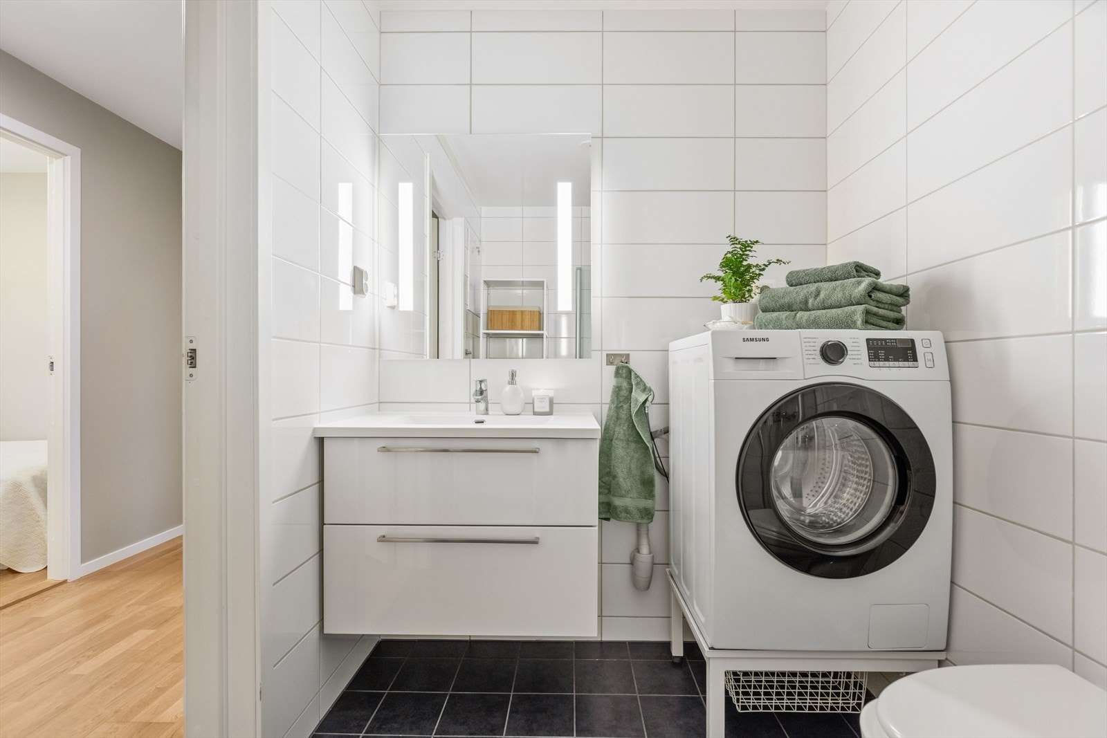 Det er montert dusjdører i glass, og badet har et pent og romslig baderomsmøblement, speil og vegghengt WC. Galleribilde