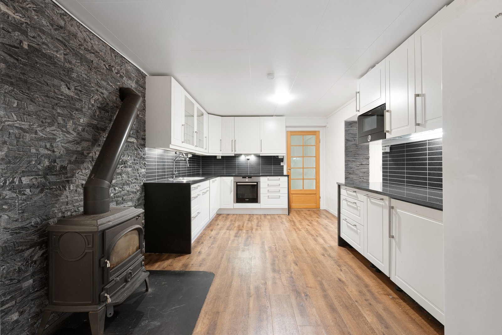 Stilrent HTH kjøkken fra 2016/2017 med integrerte hvitevarer bestående av stekeovn, induksjonstopp, micro og oppvaskmaskin Galleribilde