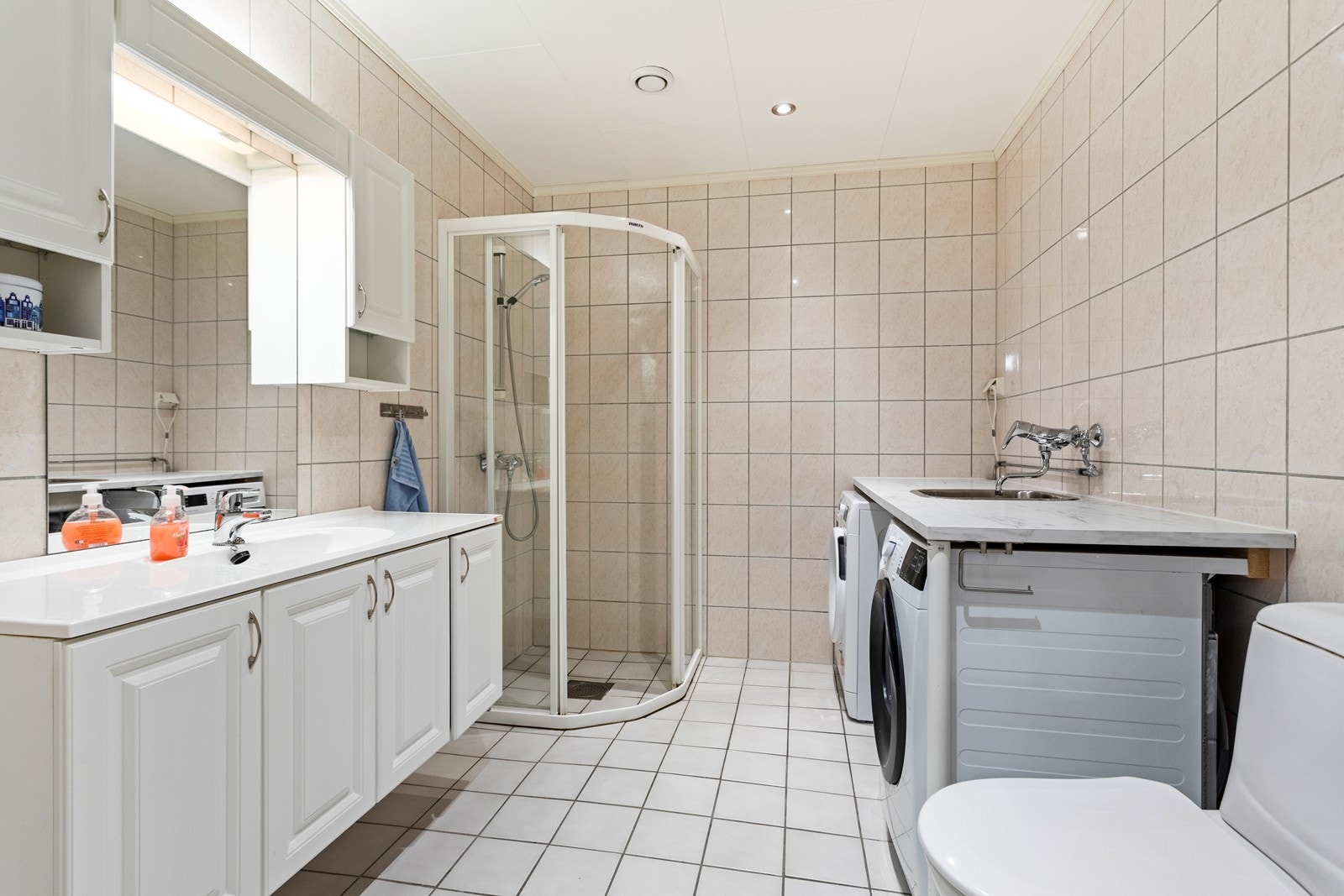 Heilflisa bad med varmekablar i golv. Prakisk innreiing med benkeplate, nedfelt skyllekar i stål og opplegg til vaskemaskin og tørketrommel. Galleribilde