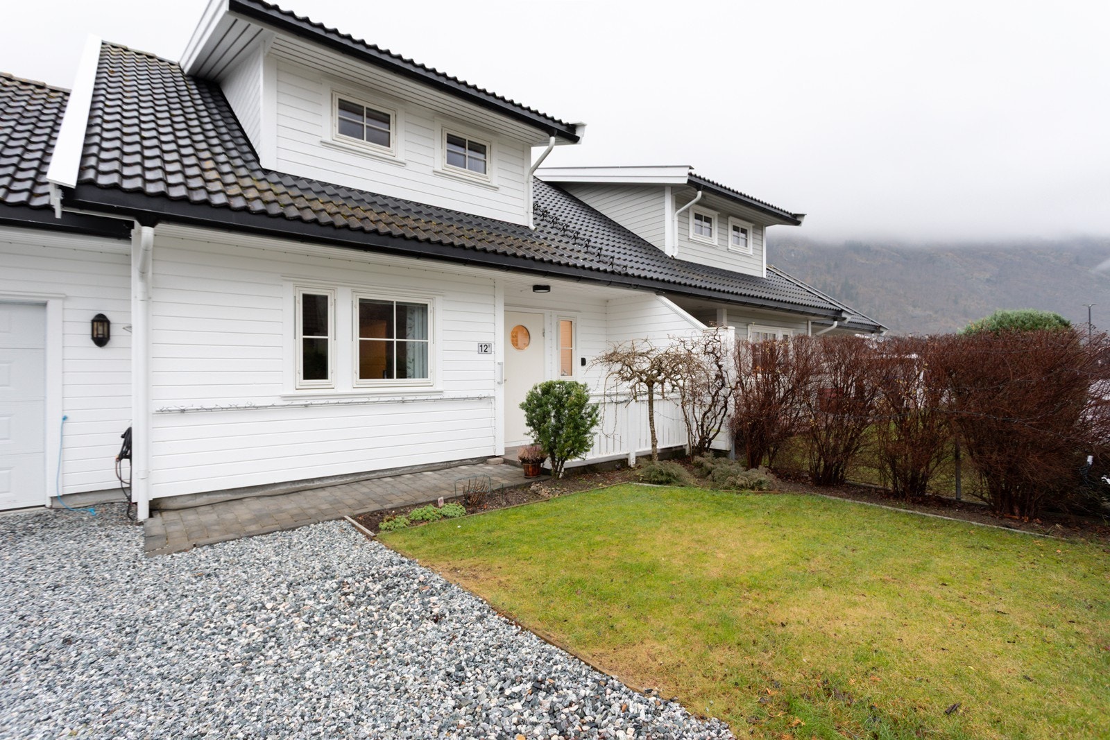 Enkel tilkomst med gruslagt tun delvis overbygd inngangsparti belagt med belegningsstein. Galleribilde