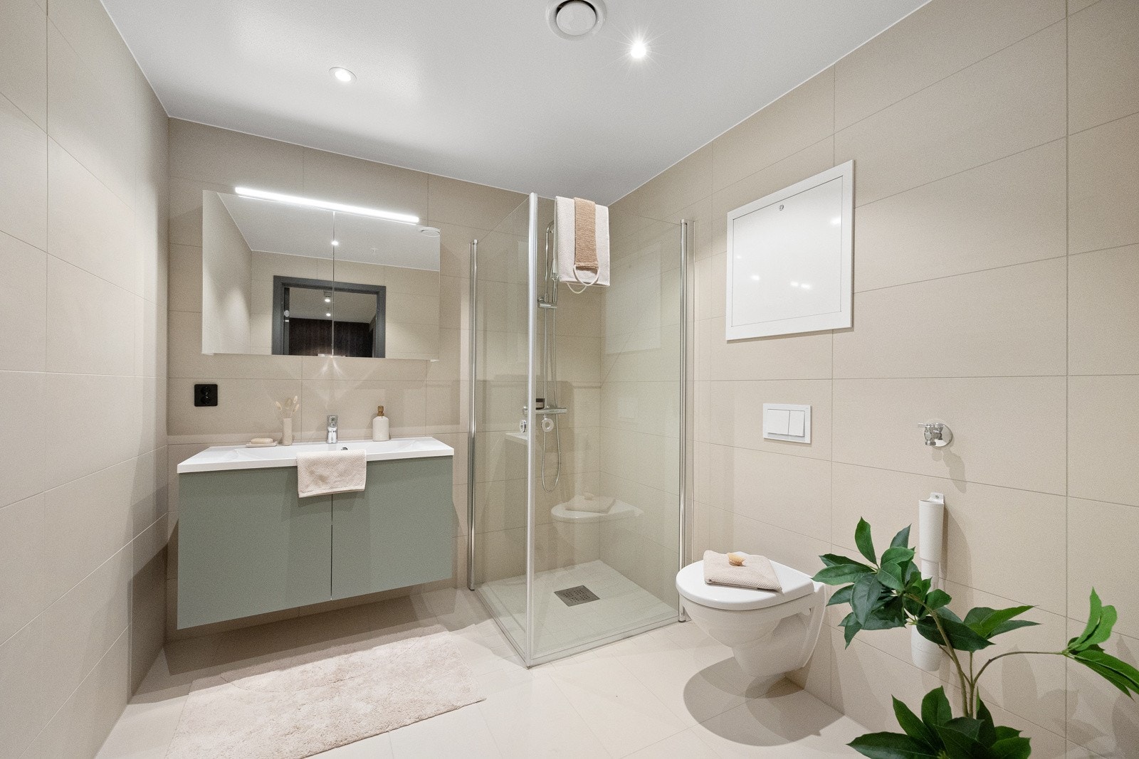 Bad med lyse, pene fliser på gulv og vegger. Opplegg for vaskemaskin. Galleribilde