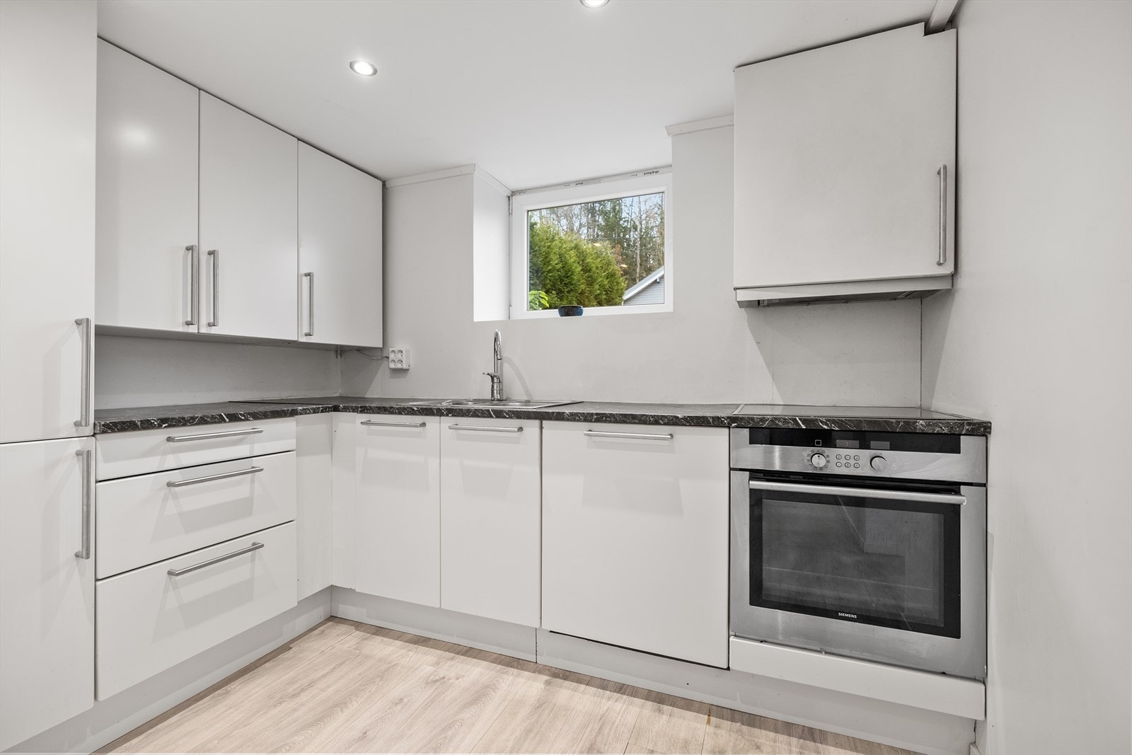 I kjelleren finnes en moderne kjøkkeninnredning fra 2021 med glatte fronter og benkeplate i høytrykkslaminat med nedfelt oppvaskkum i rustfritt Galleribilde