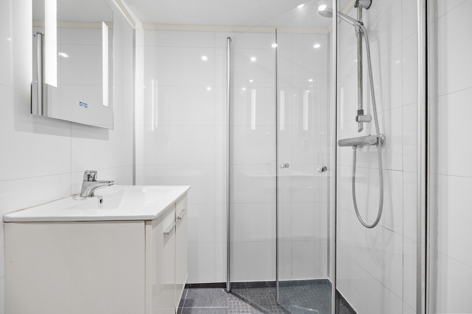 Det er utstyrt med innredning med nedfelt servant, vegghengt speil med lys, dusjhjørne med glassvegger og gulvmontert toalett. Galleribilde