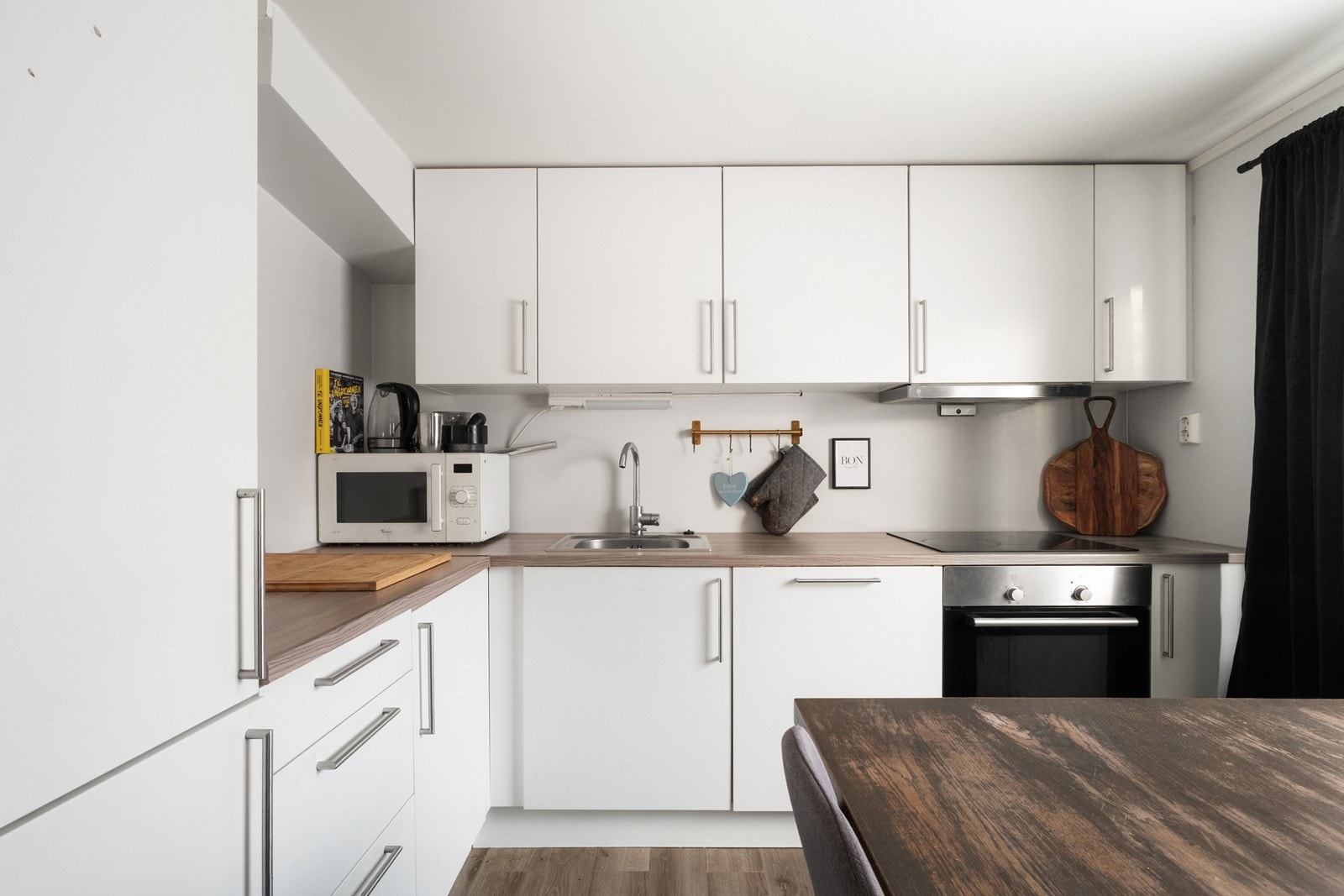 Kjøkkeninnredning med glatte, hvite fronter og integrerte hvitevarer. Galleribilde