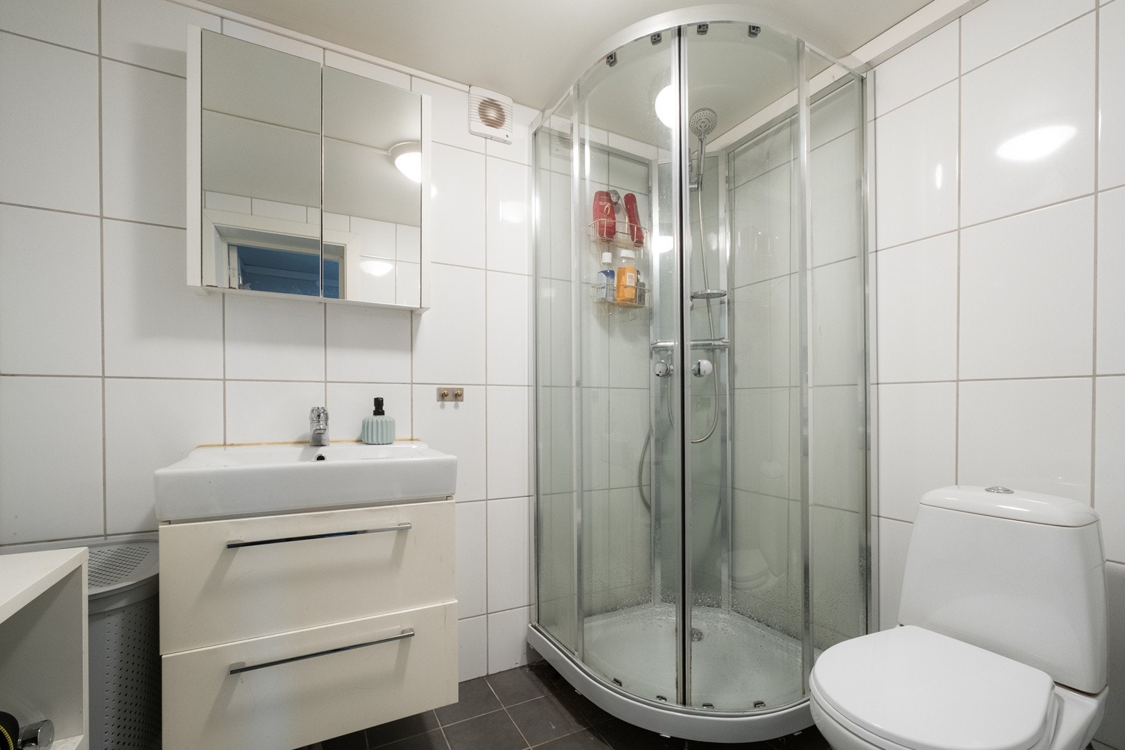 Badet er flislagt og utstyrt med wc, dusjkabinett, servant med underskap og speilskap. Galleribilde