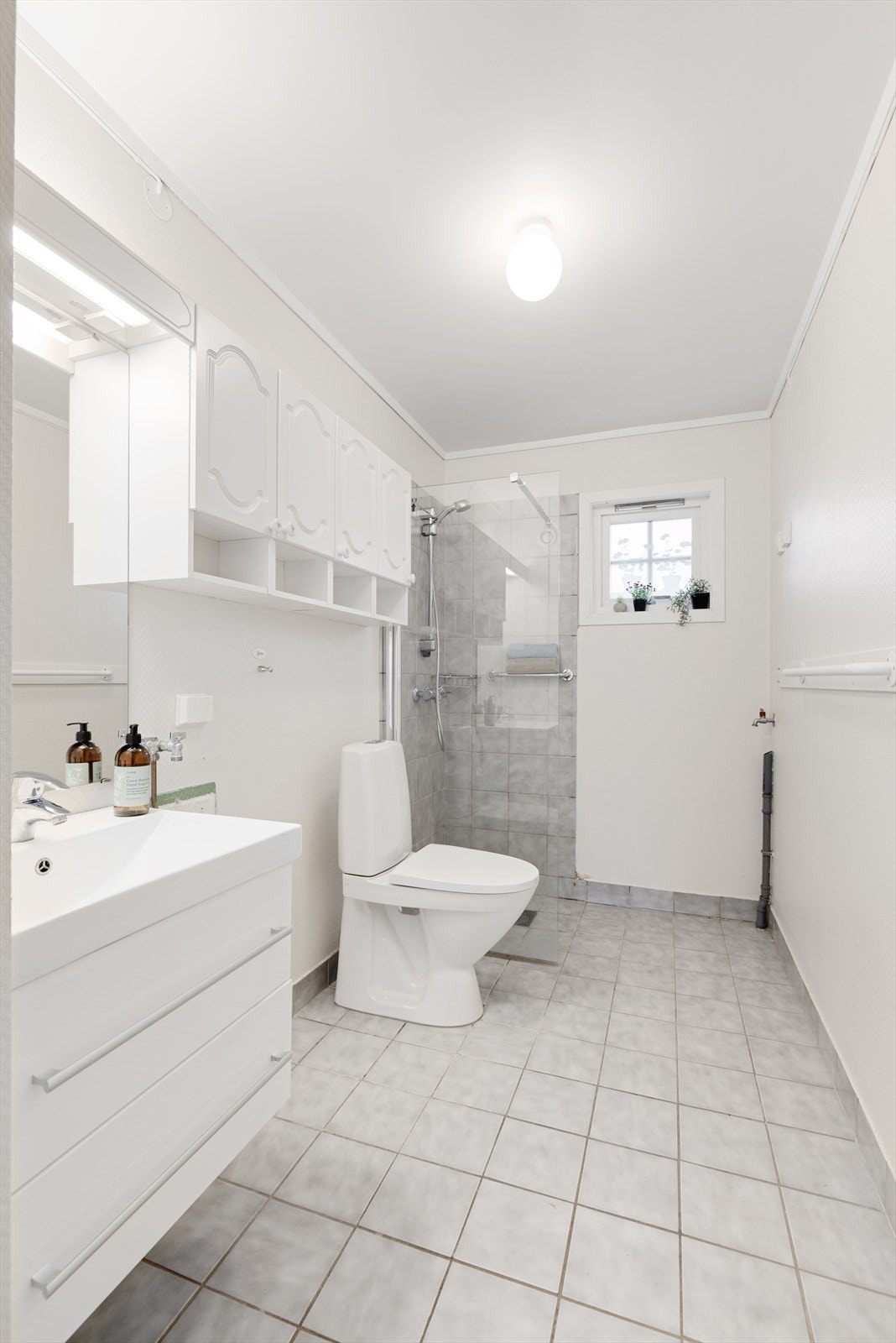 Bad/ vaskerommet er fra byggeår og inneholder heldekkende servant med underskap, flere overskap, speil og lys. Videre inneholder badet gulvmontert toalett, dusjnisje og opplegg til vaskemaskin. Galleribilde