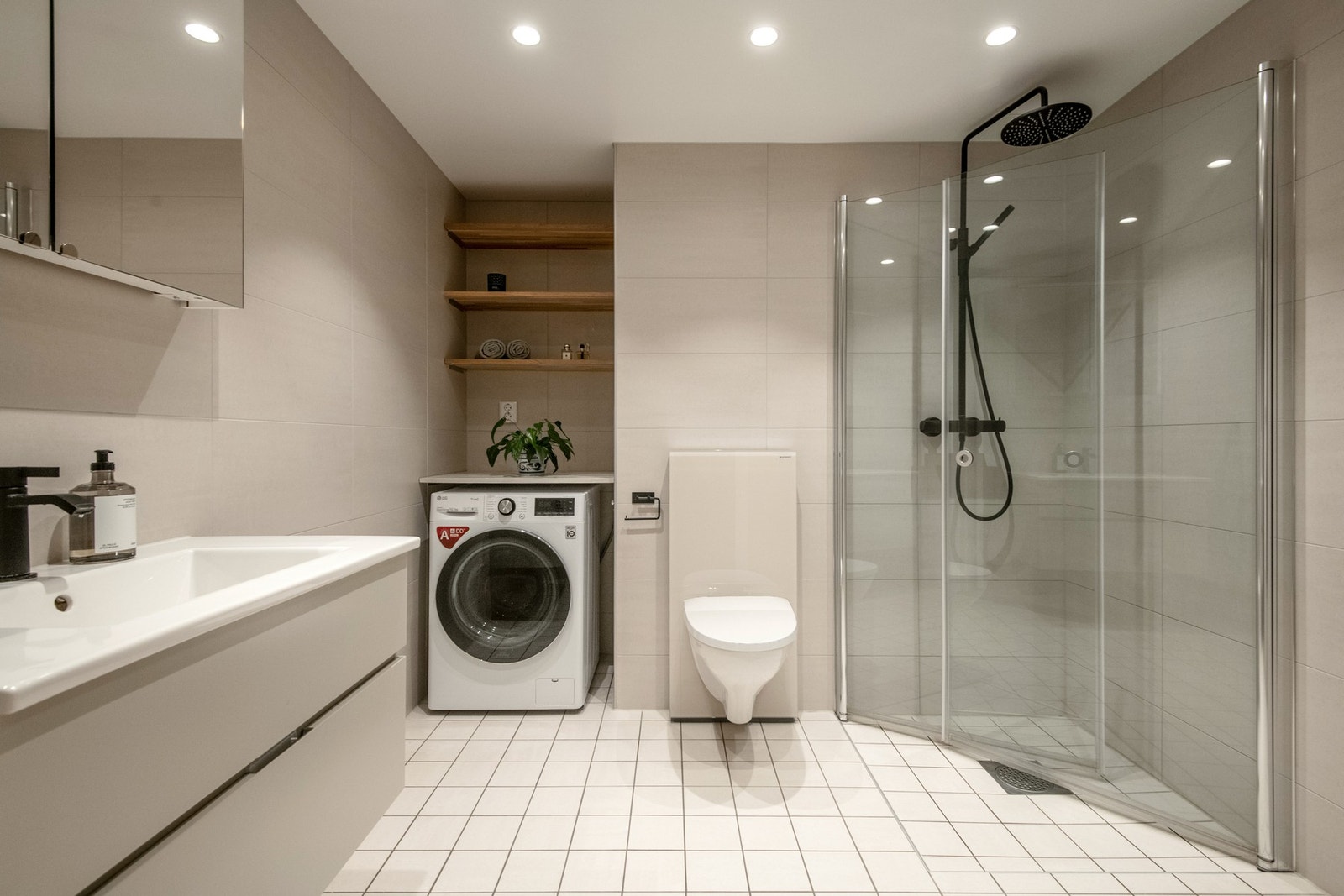 Badet fremstår som delikat og moderne med lyse flislagte overflater og behagelig gulvvarme. Innredningen består av benkeskap med glatte fronter, servant i helstøpt plate og veggskap med speilfronter. Galleribilde
