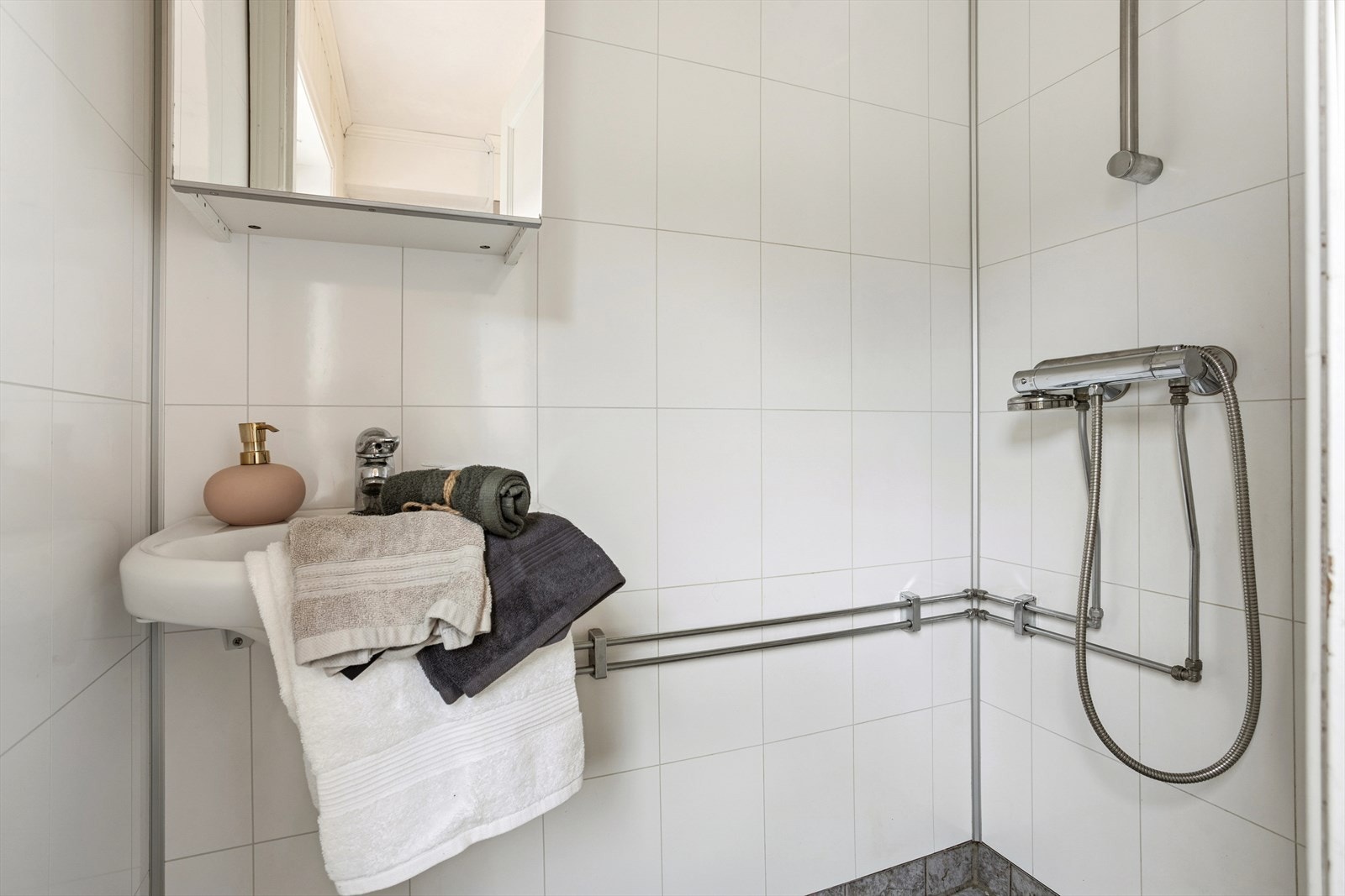 Badet har baderomsplater på veggene og fliser på gulvet, hvor det er registrert manglende fall mot sluk. Galleribilde