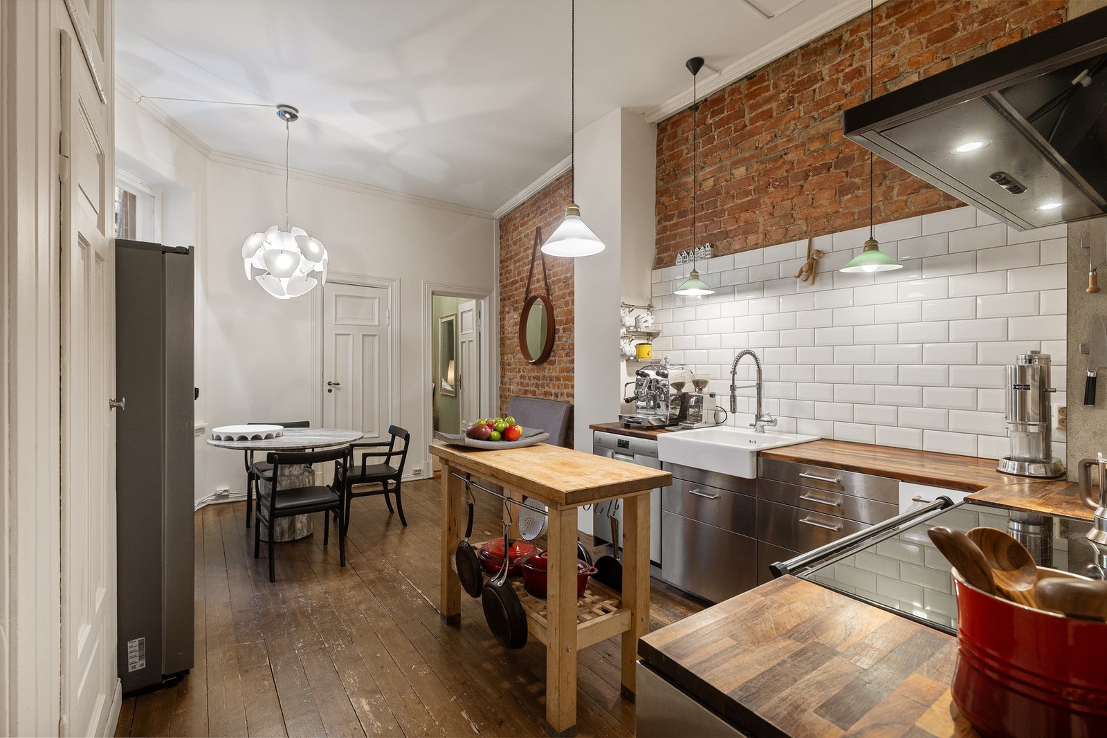 Den eksponerte teglsteinsveggen gir kjøkkenet et markant særpreg og tilfører rommet en urban karakter som står i fin kontrast til leilighetens klassiske detaljer. Galleribilde