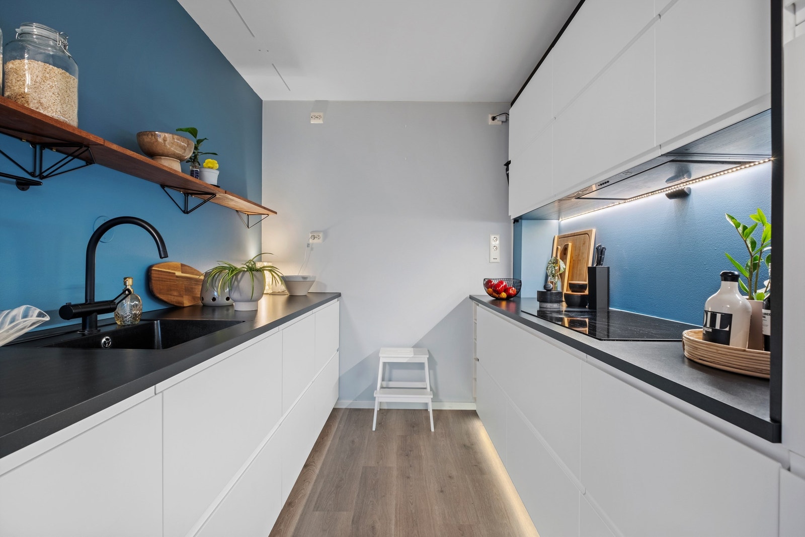 Kjøkkenet er innredet med lyse slette flater og benkeplate i kontrast og har rikelig med skap- og benkeplass. Galleribilde