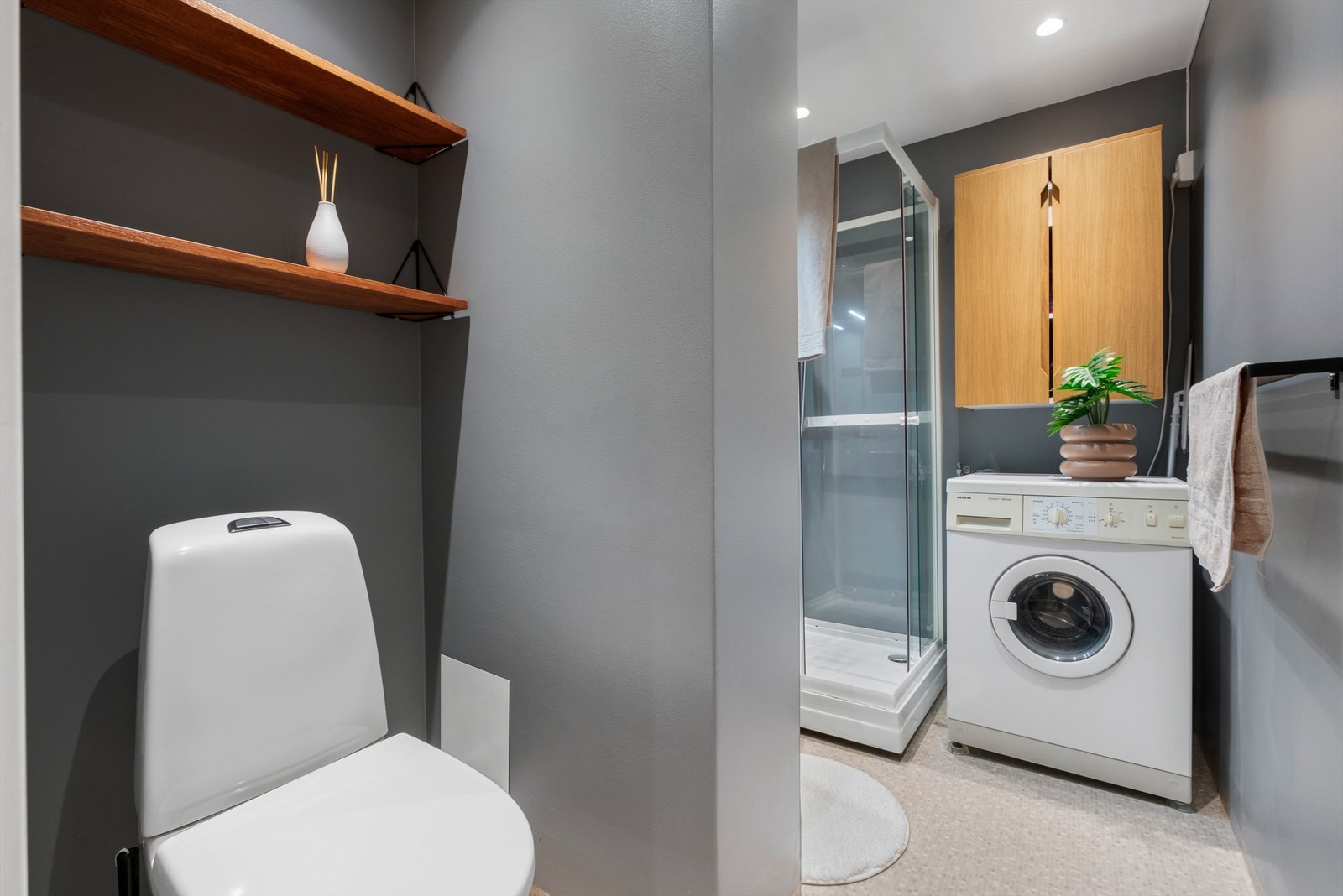 Videre er badet innredet med servantskap med speil og lys, dusjkabinett og toalett. Galleribilde