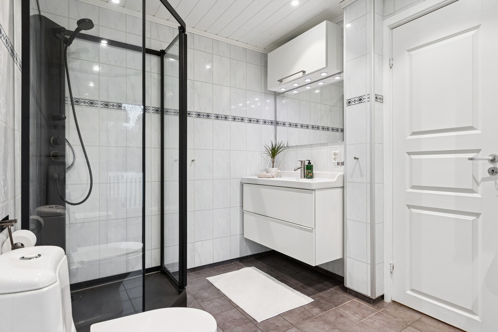 Badet i første etasje er flislagt med tidløse flis, og har vegghengt baderomsinnredning med praktiske skuffer for oppbevaring. Varmekabel i gulv dusjkabinett og wc. Galleribilde