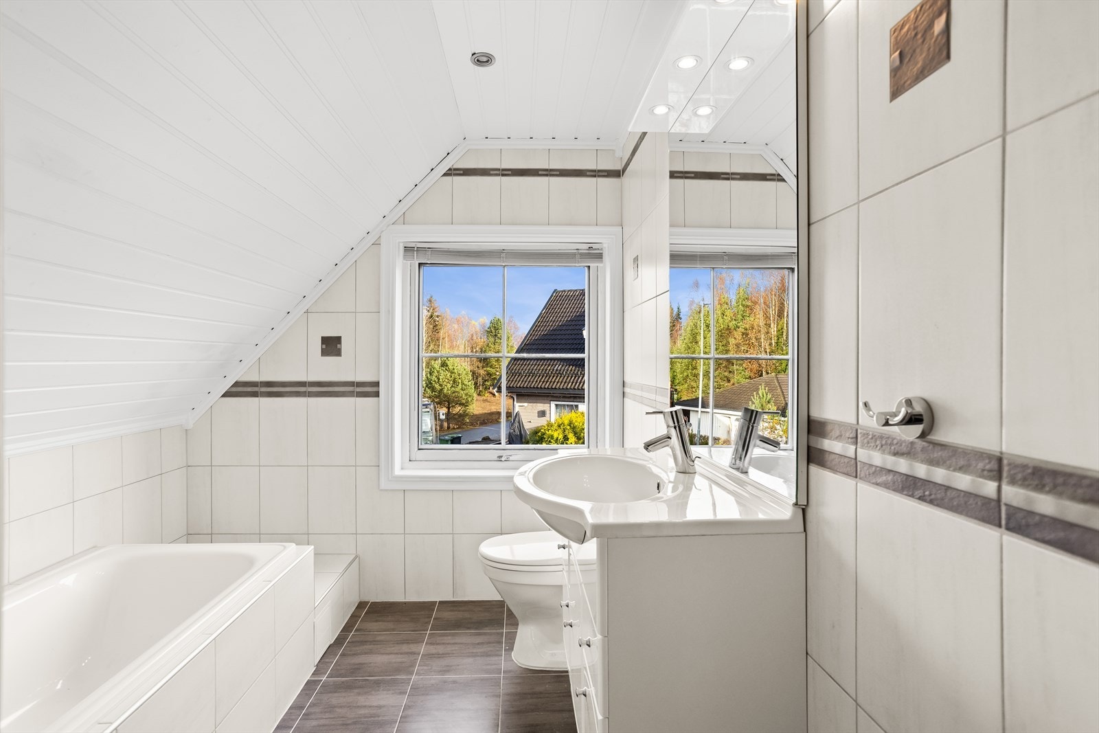 Badet i andre etasje har flislagte overflater med gulvvarme. Badet byr på servant, wc og badekar Galleribilde