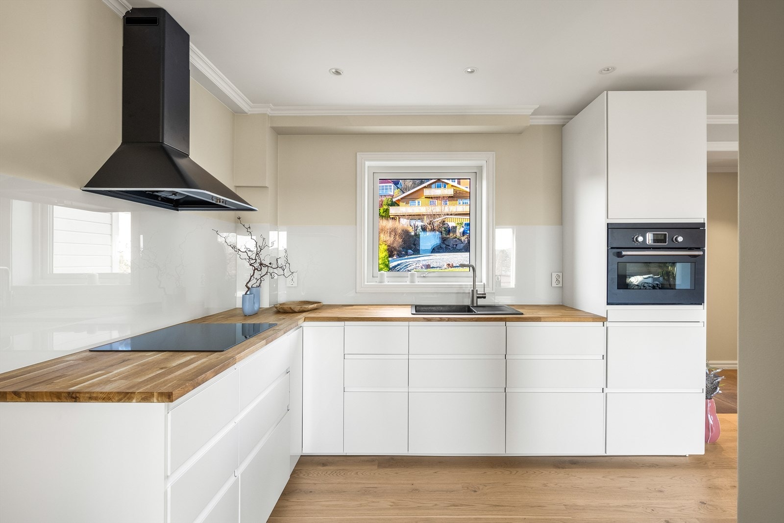 Elegant og moderne kjøkkeninnredning fra 2025 med hvite slette fronter og benkeplate av slitesterk heltre. Galleribilde