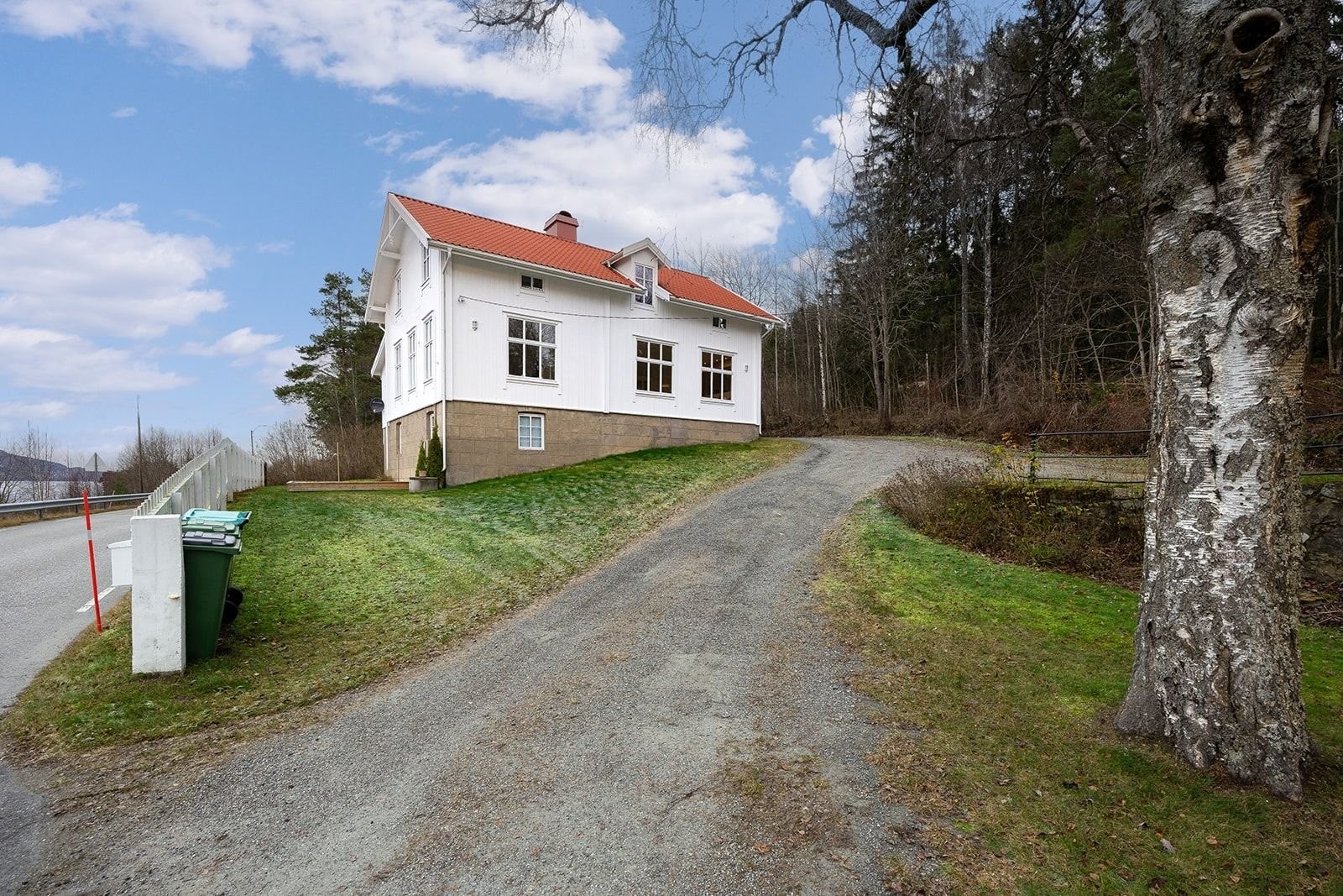 Fasade sett fra veien. Veien nedefor huset er svært lite trafikkert og tog og E6 går i tunnel i fjellet bak. Galleribilde