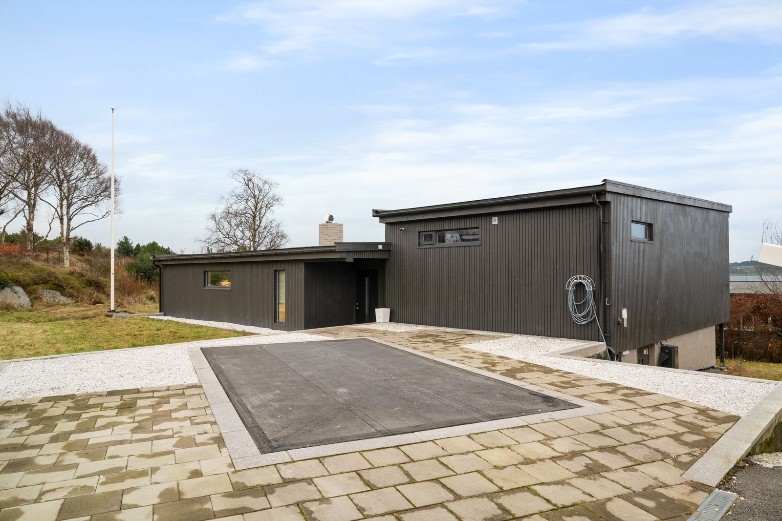 Representativ adkomst med stor innkjørsel og eksklusiv, nedfellbar bilheis som gir direkte tilgang til underetasjen. Galleribilde