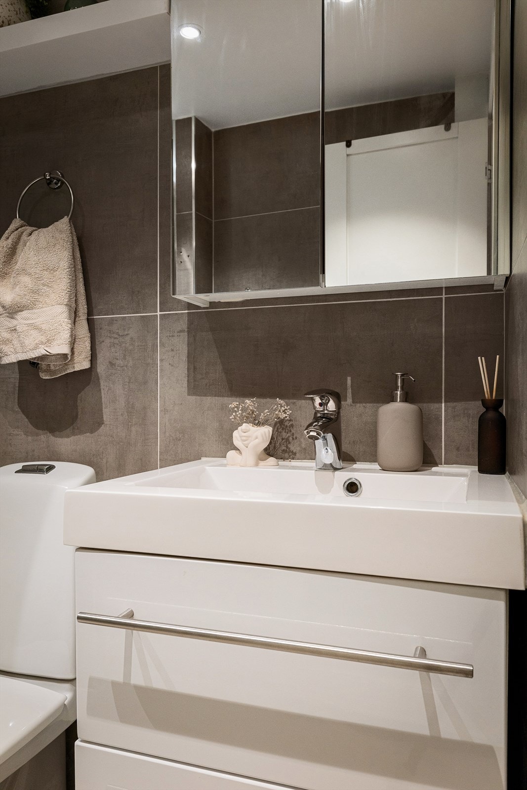 Videre har badet servant med skuffeseksjon og speil med plass til oppbevaring Galleribilde