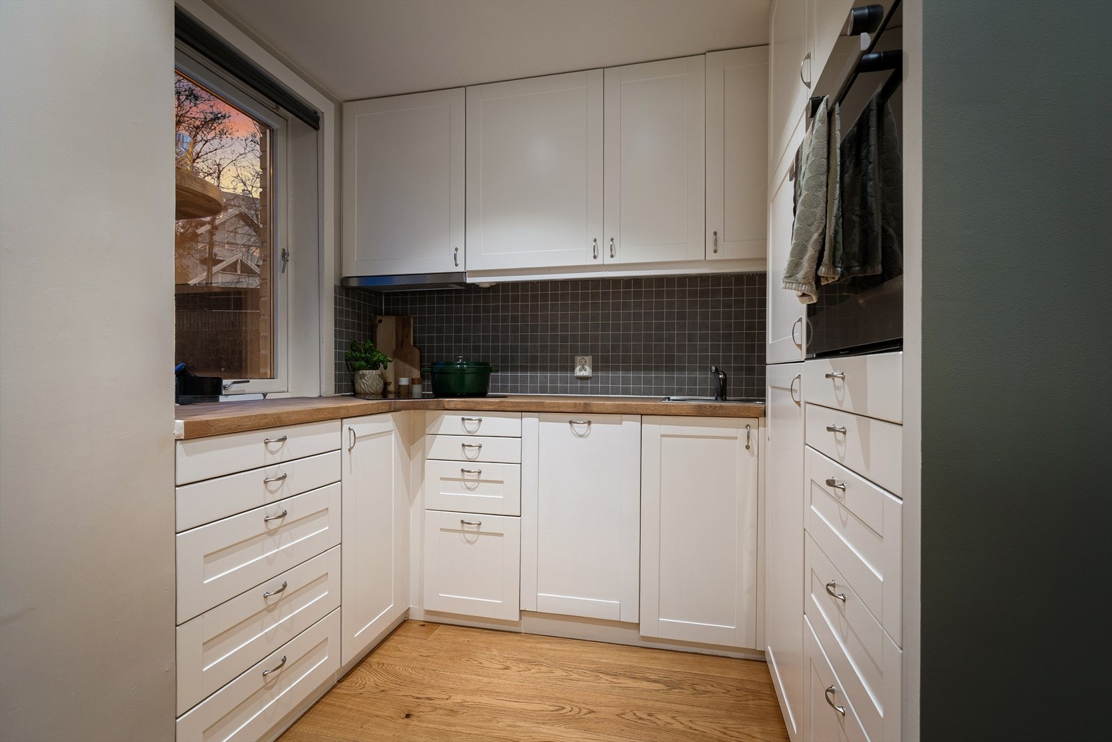 Kjøkkenet har en tidløs innredning med profilerte fronter fra IKEA. Benkeplaten er av heltre. Kjøkkenet har integrert kjøl/fryseskap, oppvaskmaskin, platetopp og stekeovn Galleribilde