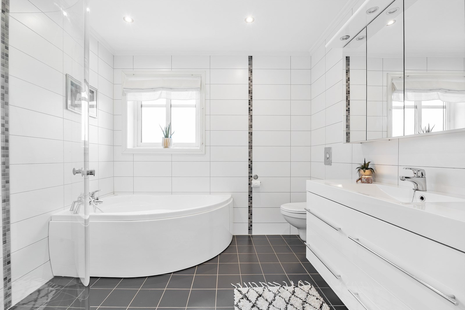 Pent baderom med flislagte gulv og vegger i tidløse fargetoner. Galleribilde