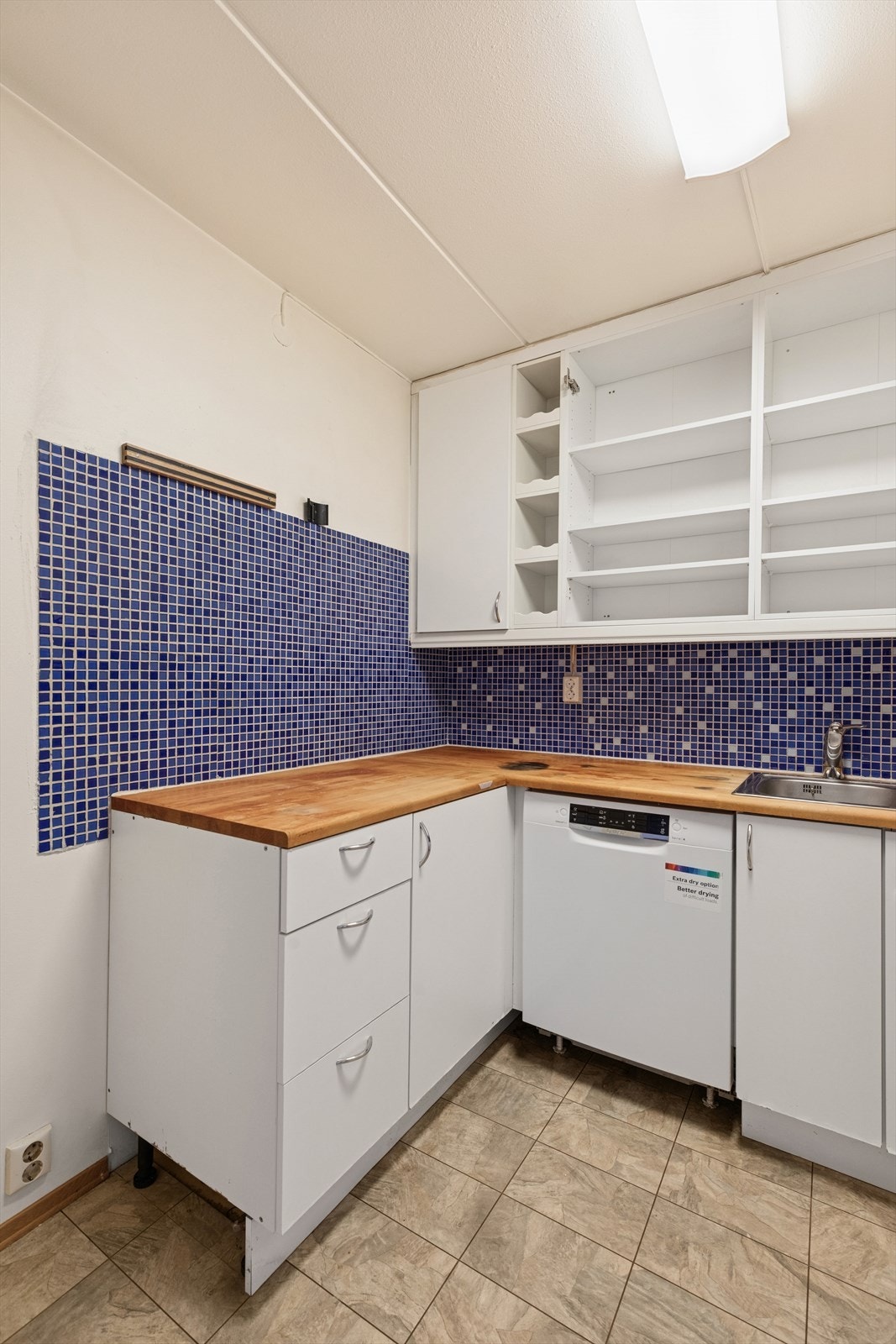 Eldre kjøkkeninnredning med glatte fronter og benkeplate i tre. Galleribilde