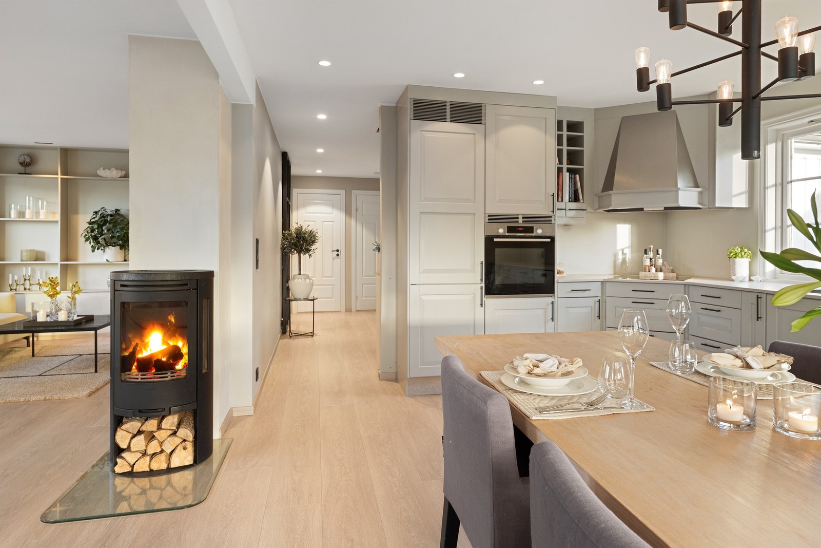 Løsningen er både praktisk og gjennomtenkt, med integrerte hvitevarer, induksjonstopp, komfyrvakt og god belysning over benkeplate. Kjøkkenet ligger i åpen løsning mot stuen, noe som skaper et sosialt og luftig allrom. Galleribilde