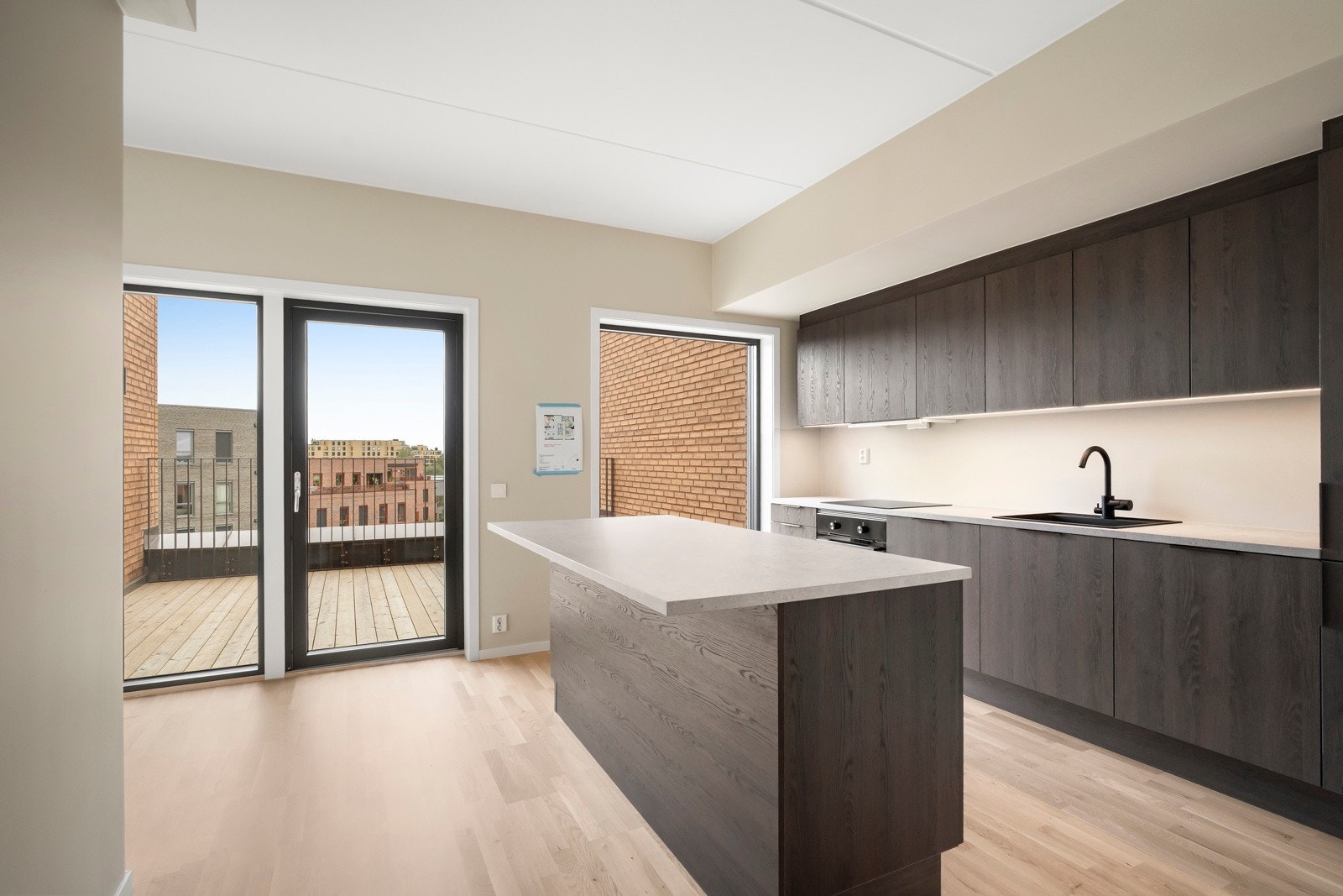 Den åpne løsningen mot stuen gjør kjøkkenet lyst og sosialt, med gulv i lys eikeparkett og vannbåren varme som holder temperaturen behagelig under matlaging og måltider. Galleribilde