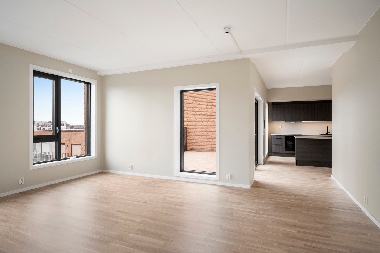 Den åpne planløsningen mot kjøkkenet skaper et lyst og luftig rom, perfekt for både sofagruppe og spiseplass. Galleribilde