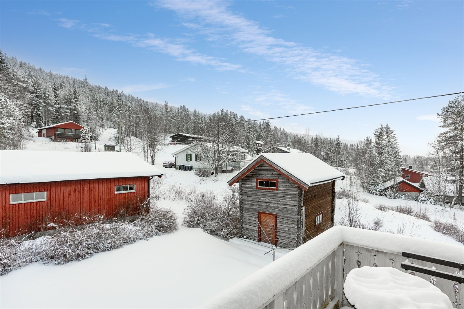 Trivelig utsyn mot gårdsplassen og nærområdet fra verandaen i andre etasje. Uthuset består av en eldre, laftet del med tilbygg i bindingsverk. Galleribilde