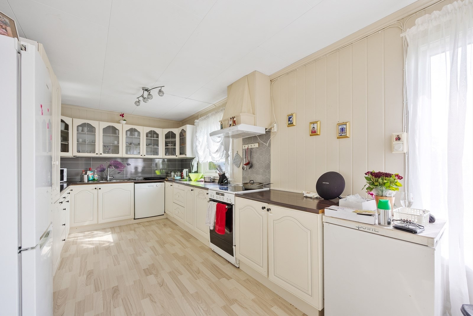 Lys kjøkkeninnredning med profilerte fronter, mørk benkeplate og kitchenboard mellom skap og benk. Galleribilde