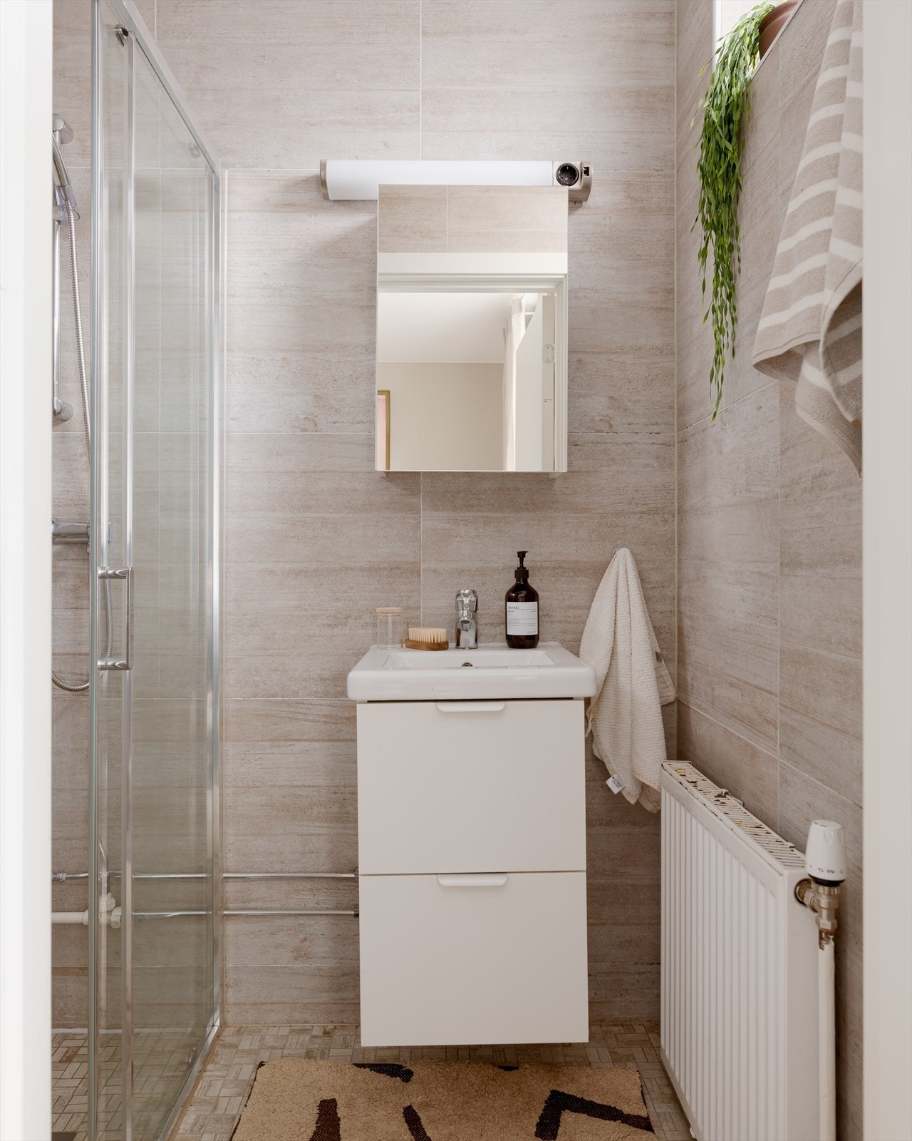 Det tidløse badet er lyst flislagt. Badet er innredet med servant, dusjhjørne med dusj rett på flis. Galleribilde