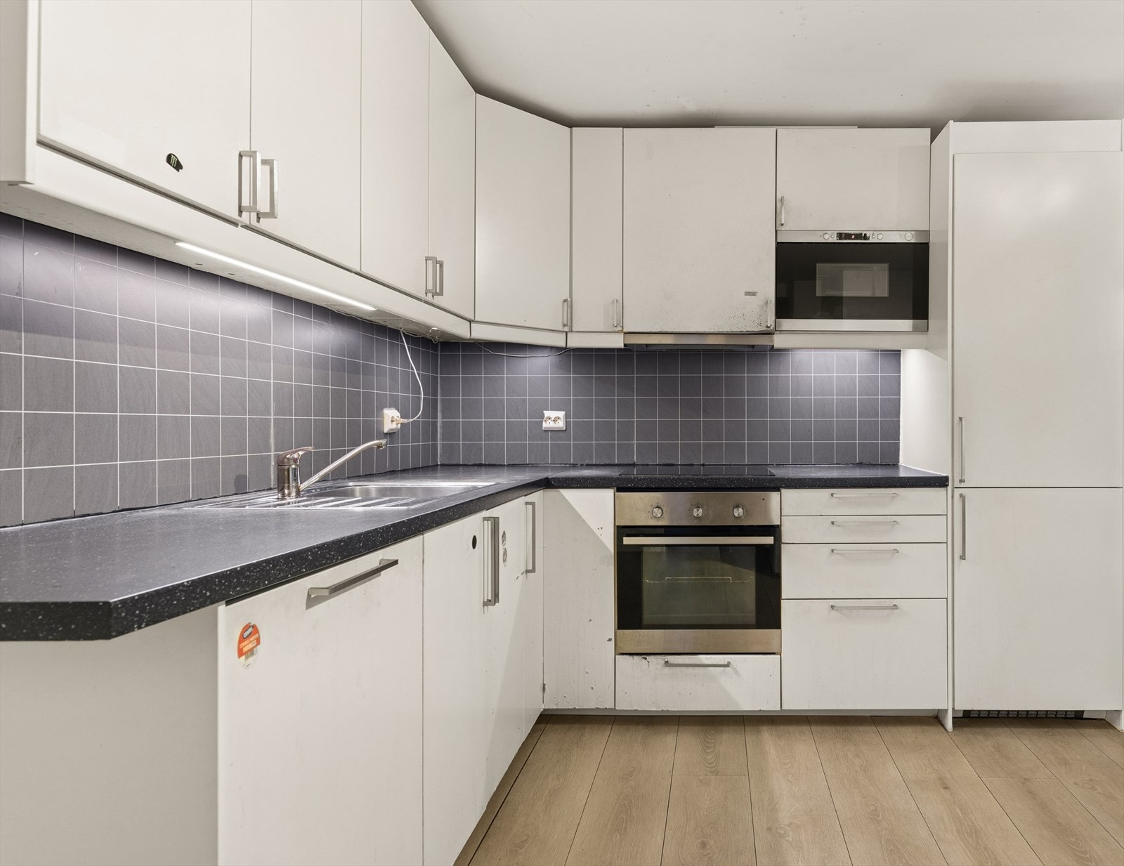 Kjøkkenet har hvite fronter, mørk benkeplate og er velutstyrt med skap og benkeplass. Galleribilde