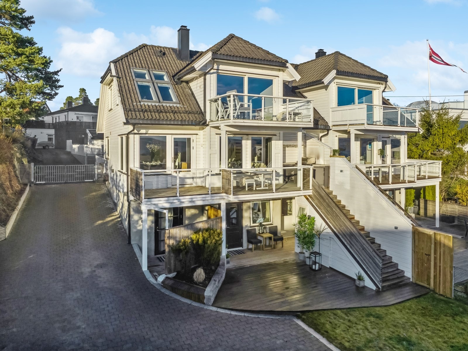 Boligen har adkomst fra asfaltert innkjørsel med varmekabler. Elektrisk port og inngjerdet tomt. Galleribilde