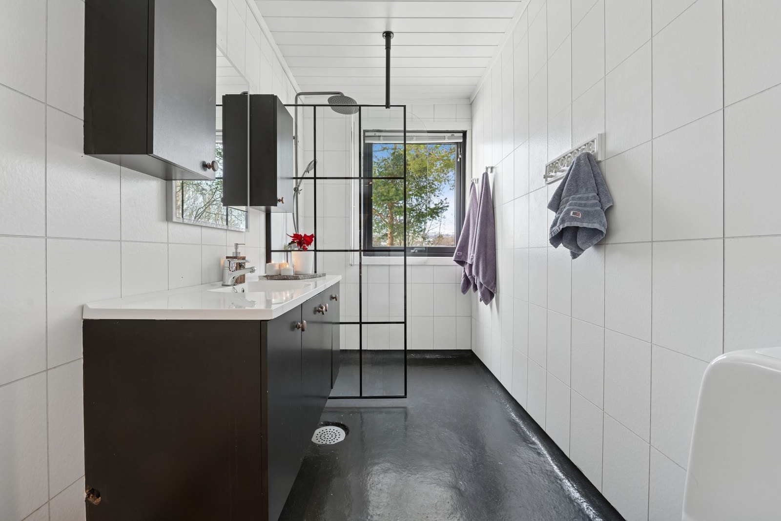 Lys og funksjonelt bad med servantinnredning, speil med lys samt dusjnisje med glassvegg og regndusj. Galleribilde