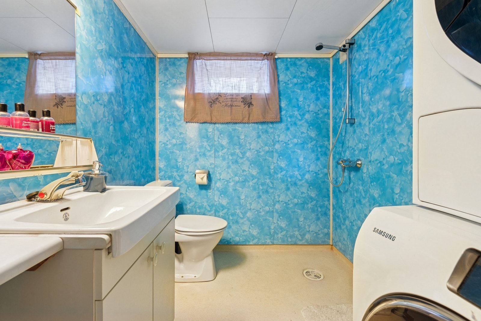 Praktisk bad i kjelleretasjen, utstyrt med opplegg for vaskemaskin, toalett samt servantinnredning med speil, og som dekker daglige behov på en funksjonell måte. Galleribilde